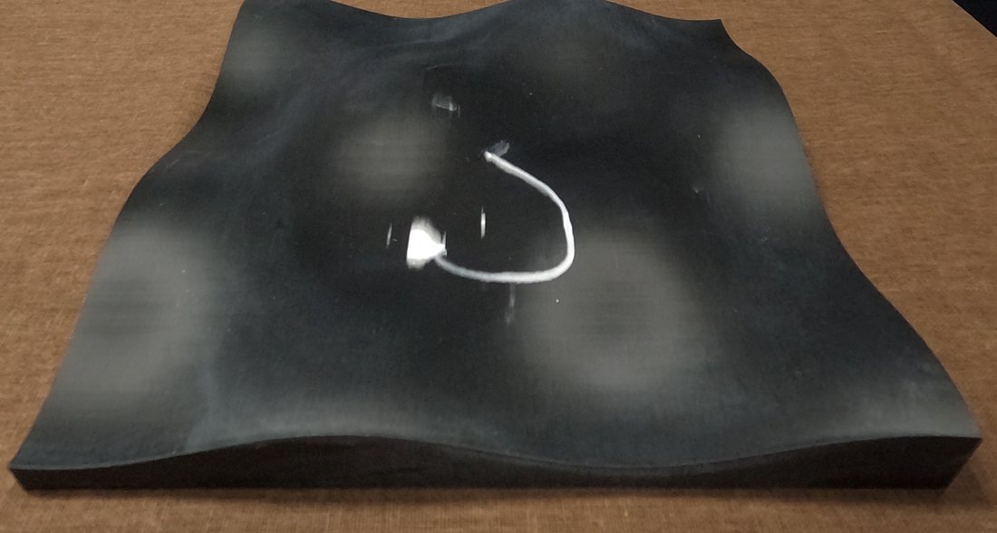 Partial figure-eight with thick, stamped white marks on a curved black surface
